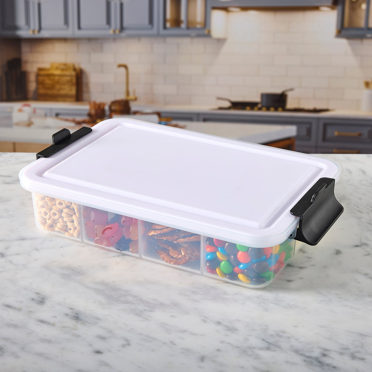 Snacklebox with seven compartments on a kitchen island, cookies visible through the clear lid