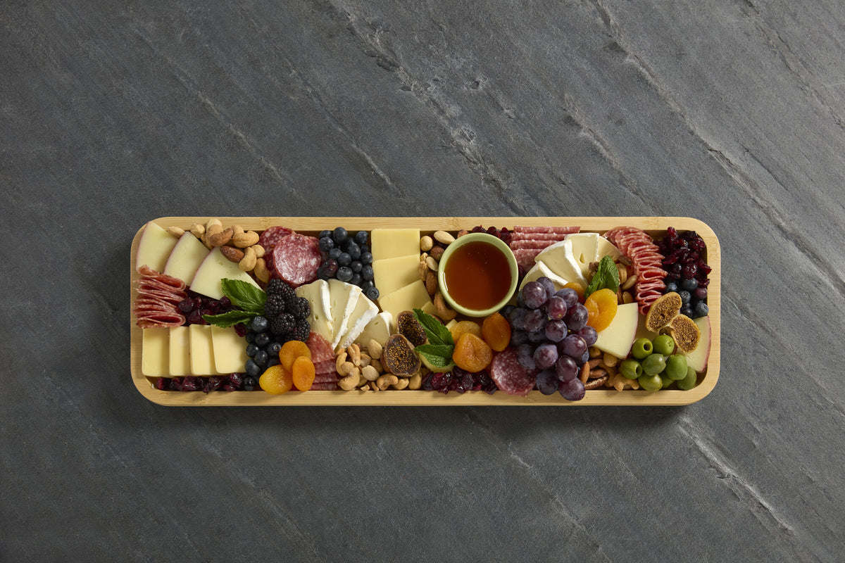 Build-a-Board bamboo cutting board filled with a colorful charcuterie spread of cheese, salami, nuts and fruit.