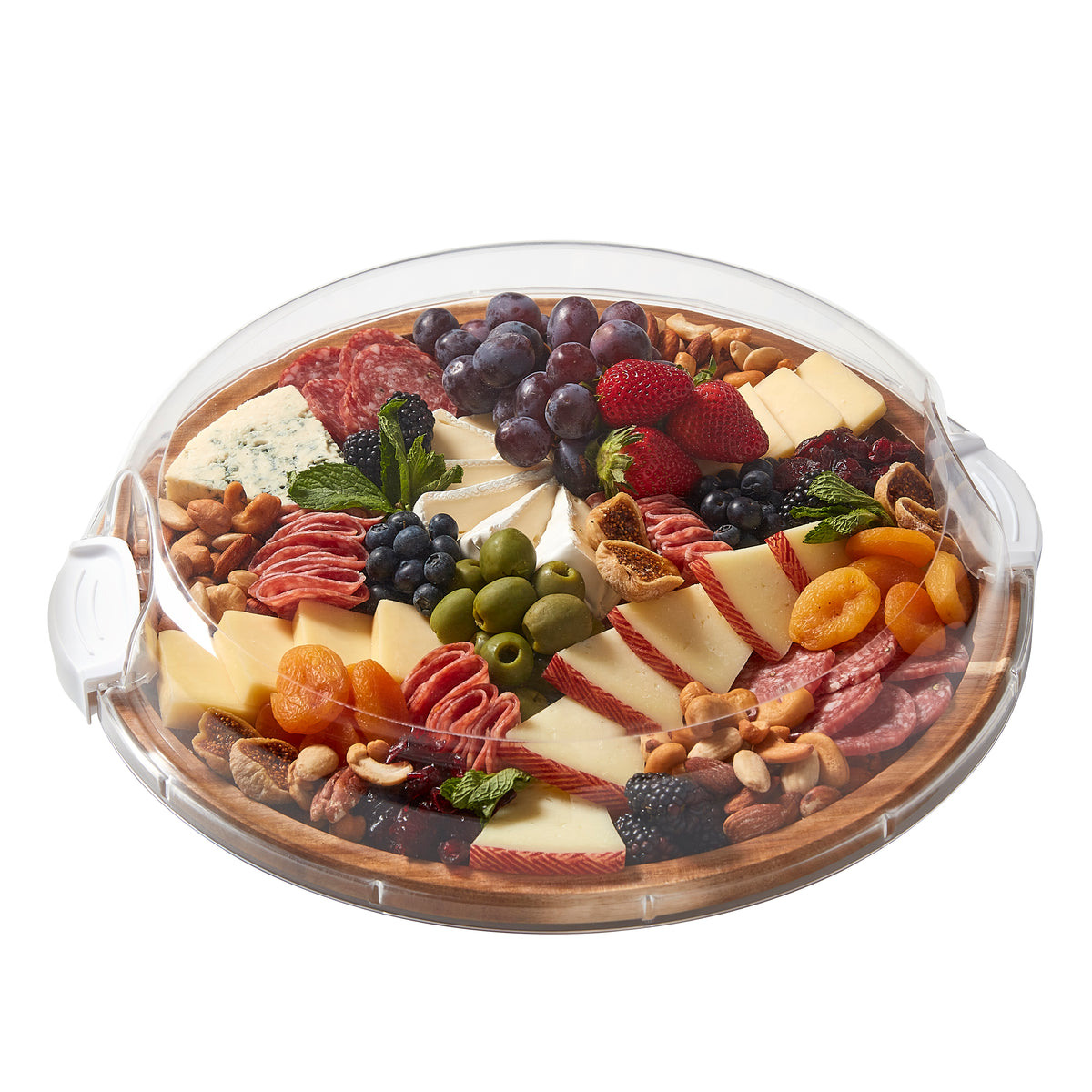 Partial view of a round glass serving dish with cheeses and fruit against a white background.