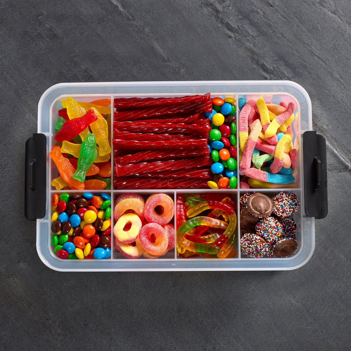 Snacklebox seven section container filled with red braided licorice and colorful gummies