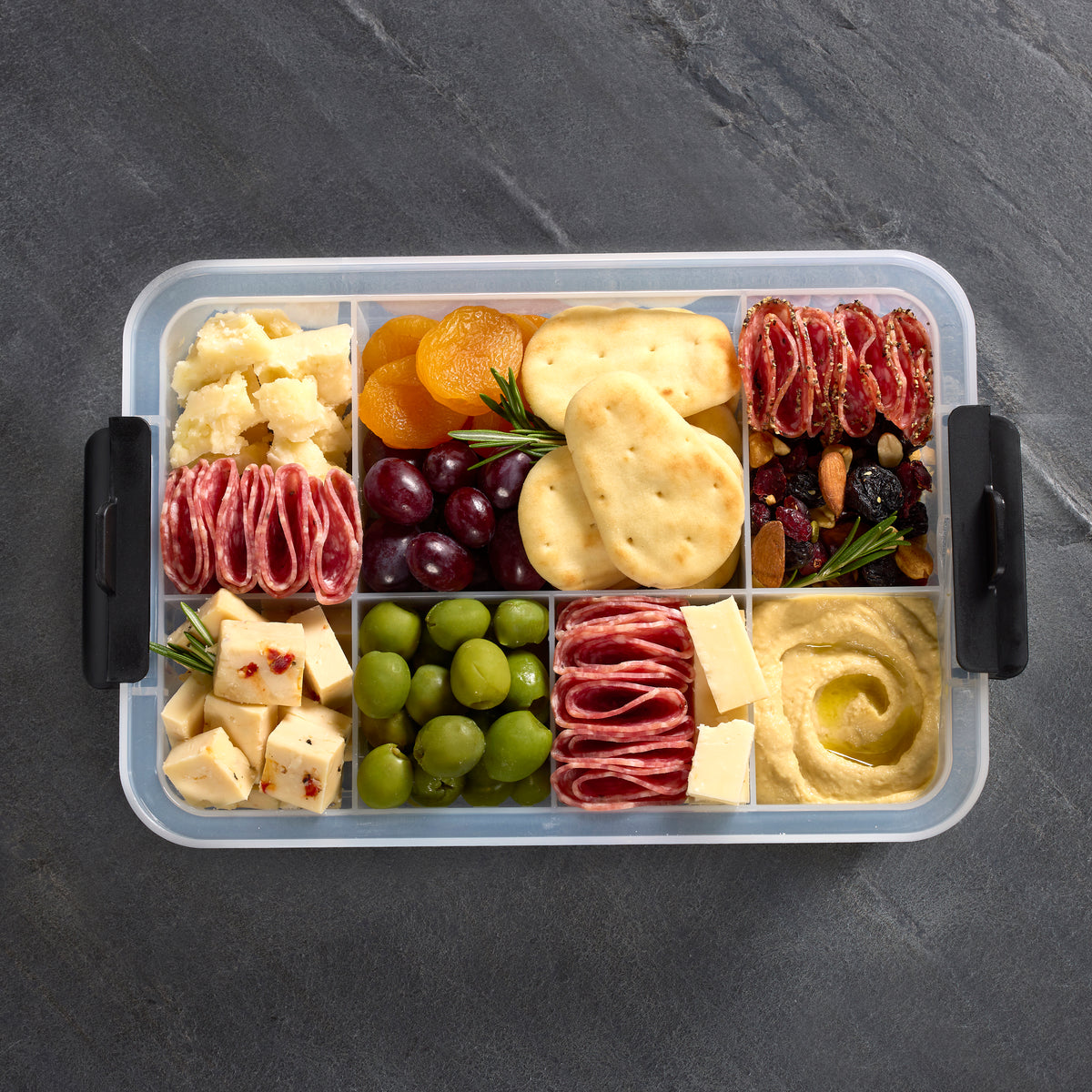 Snacklebox seven sections with cheese cubes dried apricots grapes crackers and salami slices