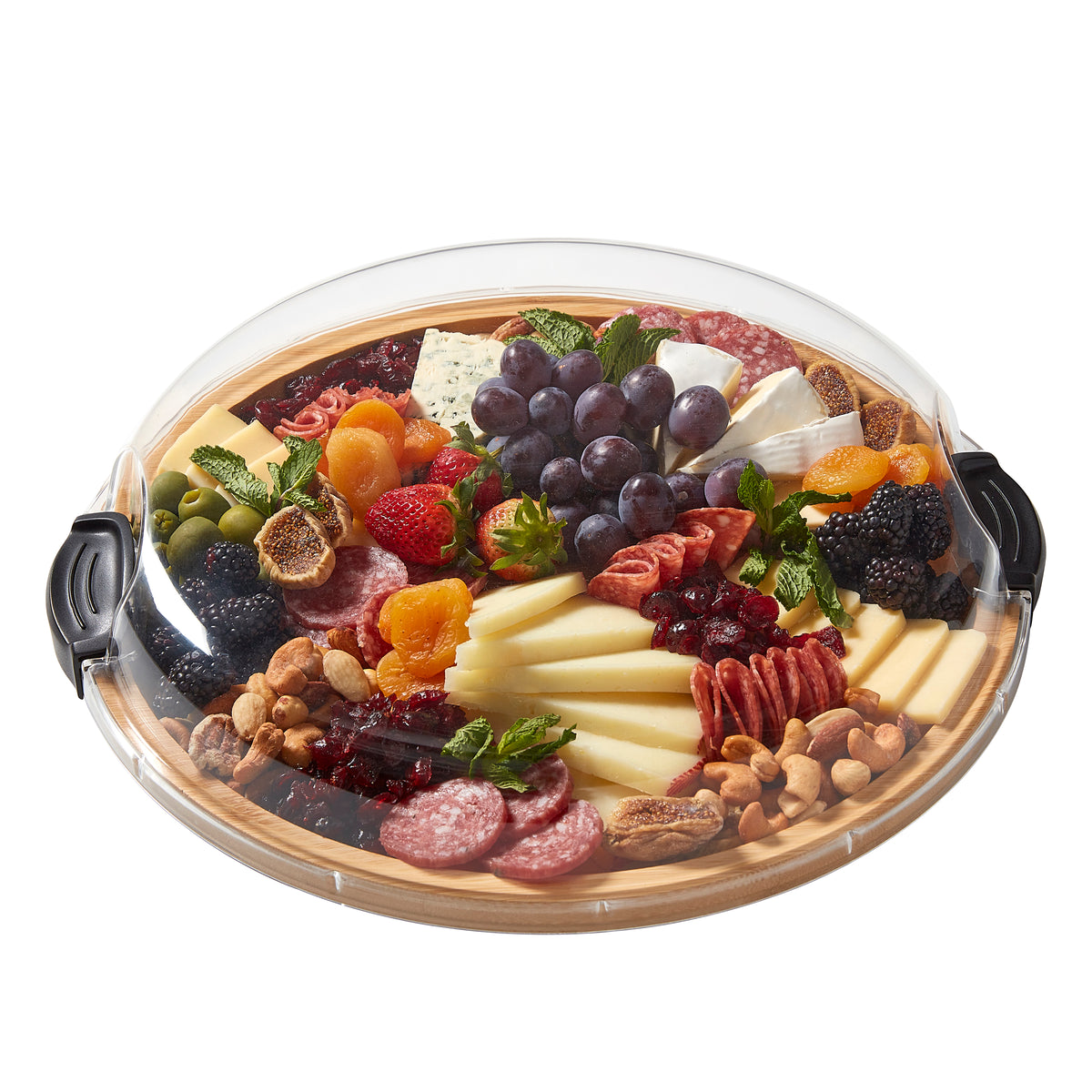 Close up of a round bamboo board under a glass cloche with cheese fruit and nuts arranged on it
