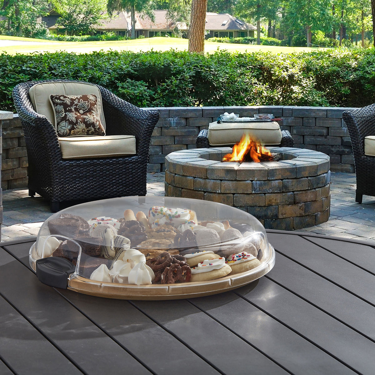 Build-a-Board Bamboo round cutting board with fruit platter under a glass dome on an outdoor patio table