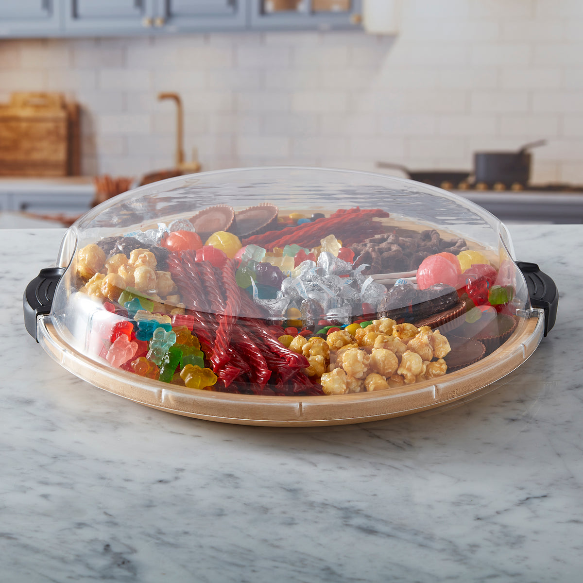 Blurred kitchen background with a dome over a snack board on a marble counter